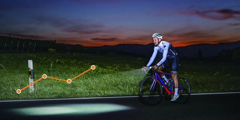 Night cyclist evaluating bicycle front light visibility on a dark road